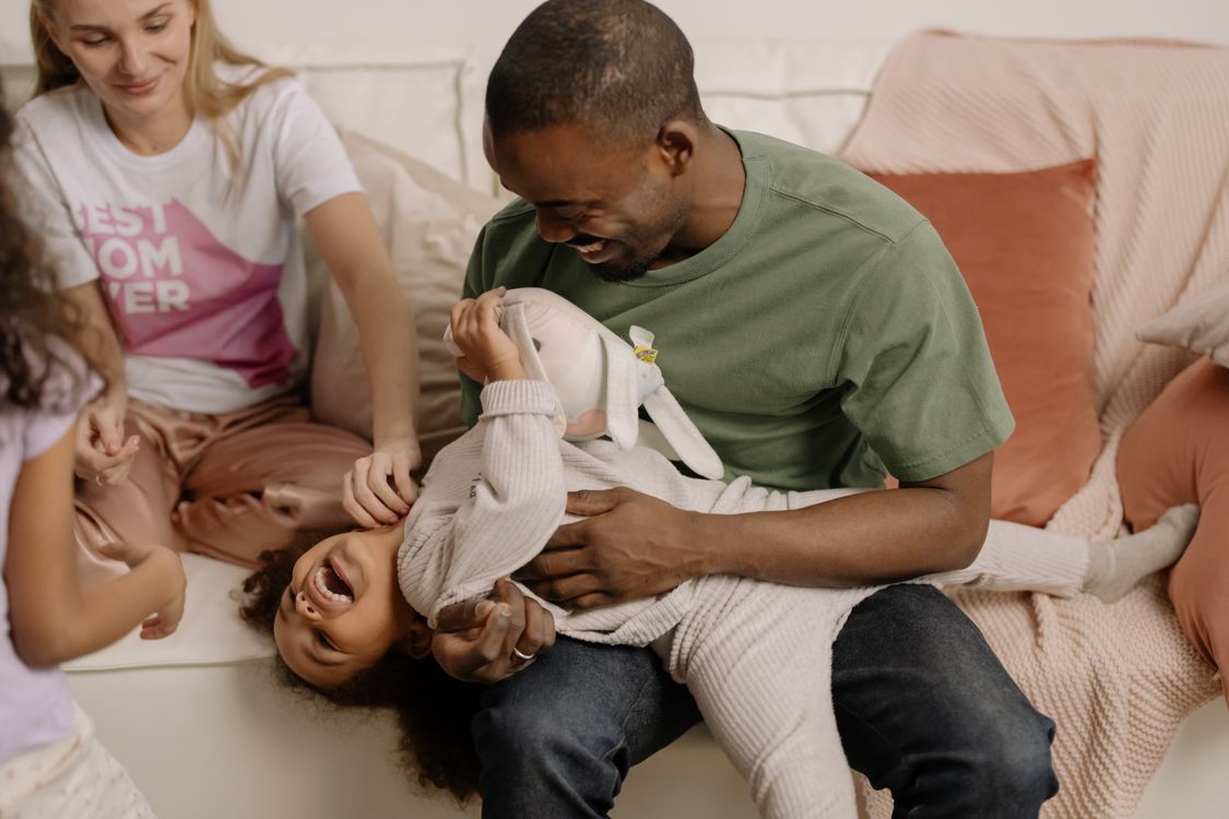 Parents and children playing together on a sofa